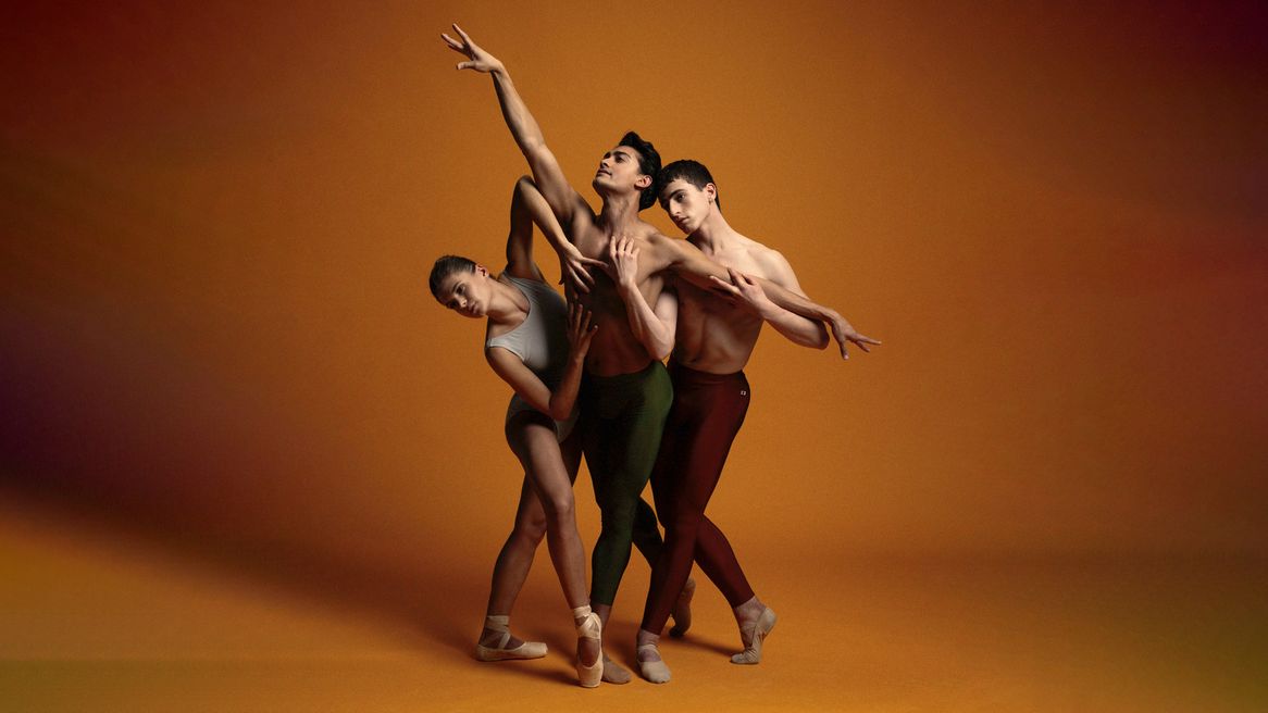 Three ballet dancers pose in various positions in front of an orange background