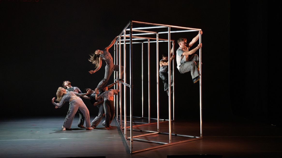 Dancers perform alongside a large metal structure