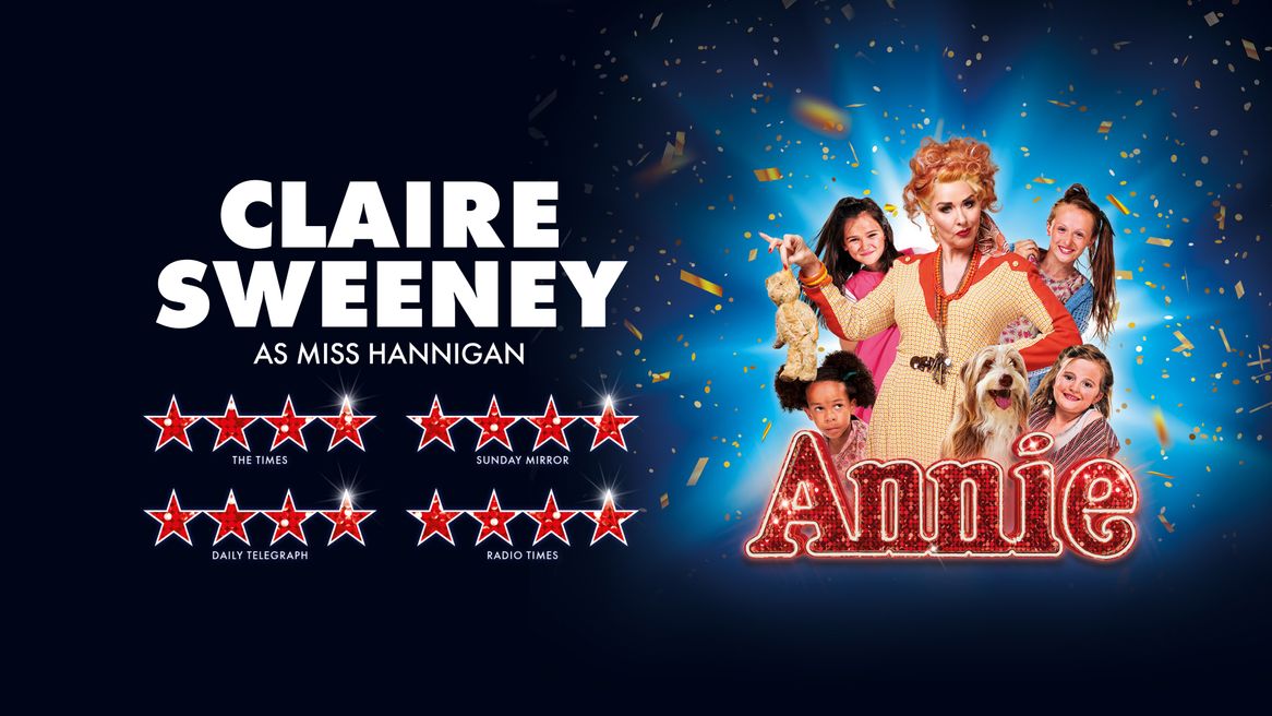 Claire Sweeney in auburn wig dressed in old fashioned house-coat holds a filthy teddy bear by the ear surrounded by girls