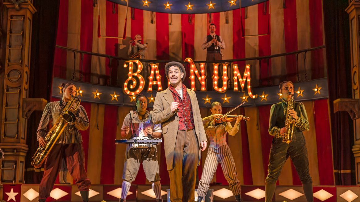 Lee Mead as Barnum sings in front of circus performers playing instruments