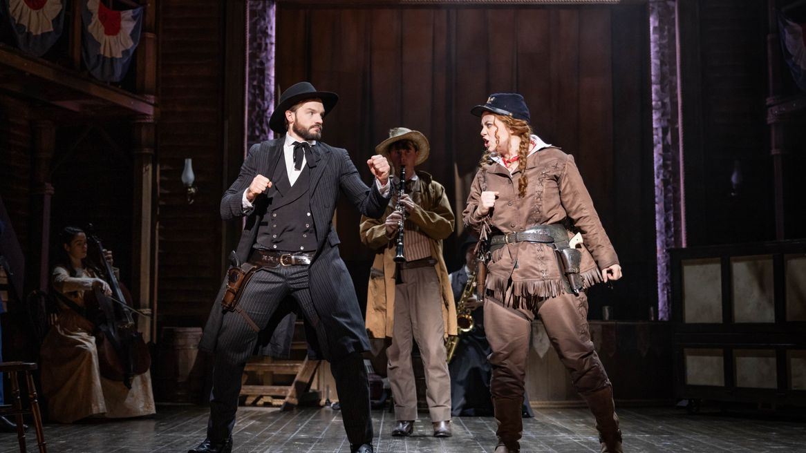 A man and a woman in Western outfits argue together