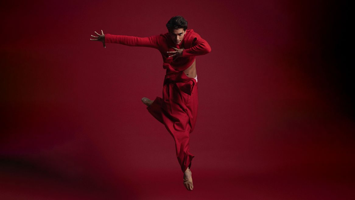 A male dancer poses in front of a red background