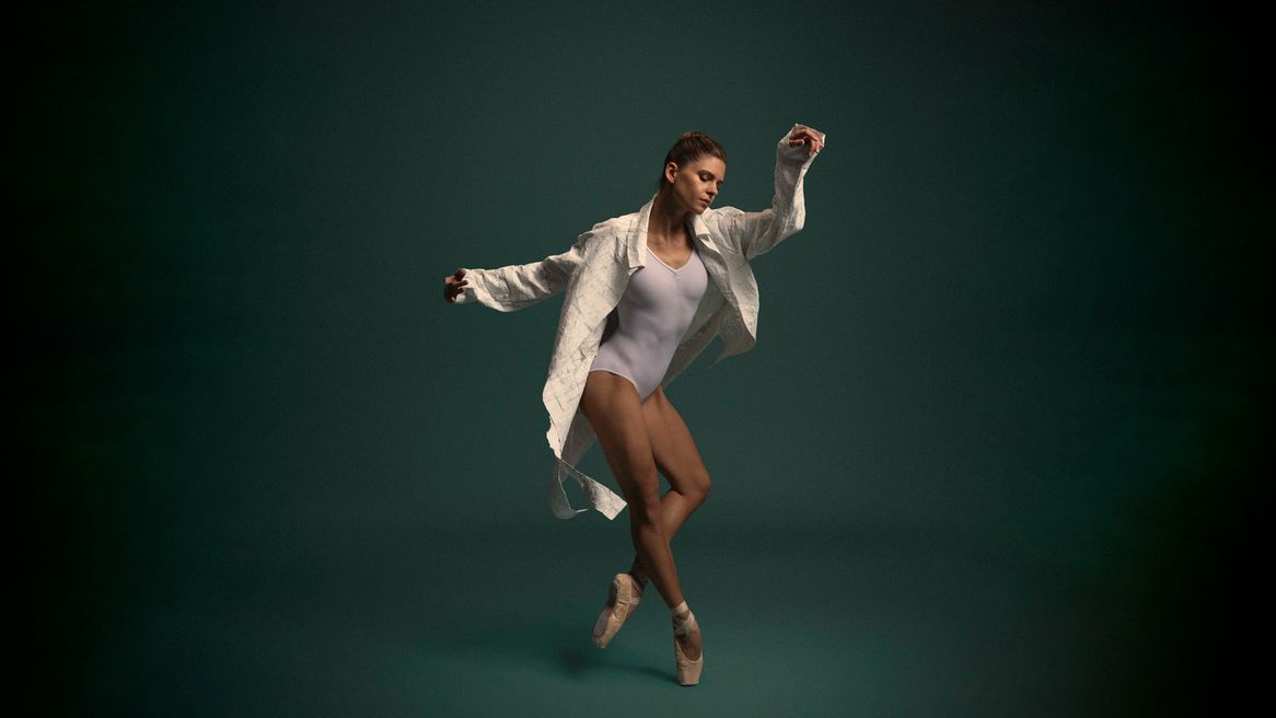 A female dancer poses in front of a green background