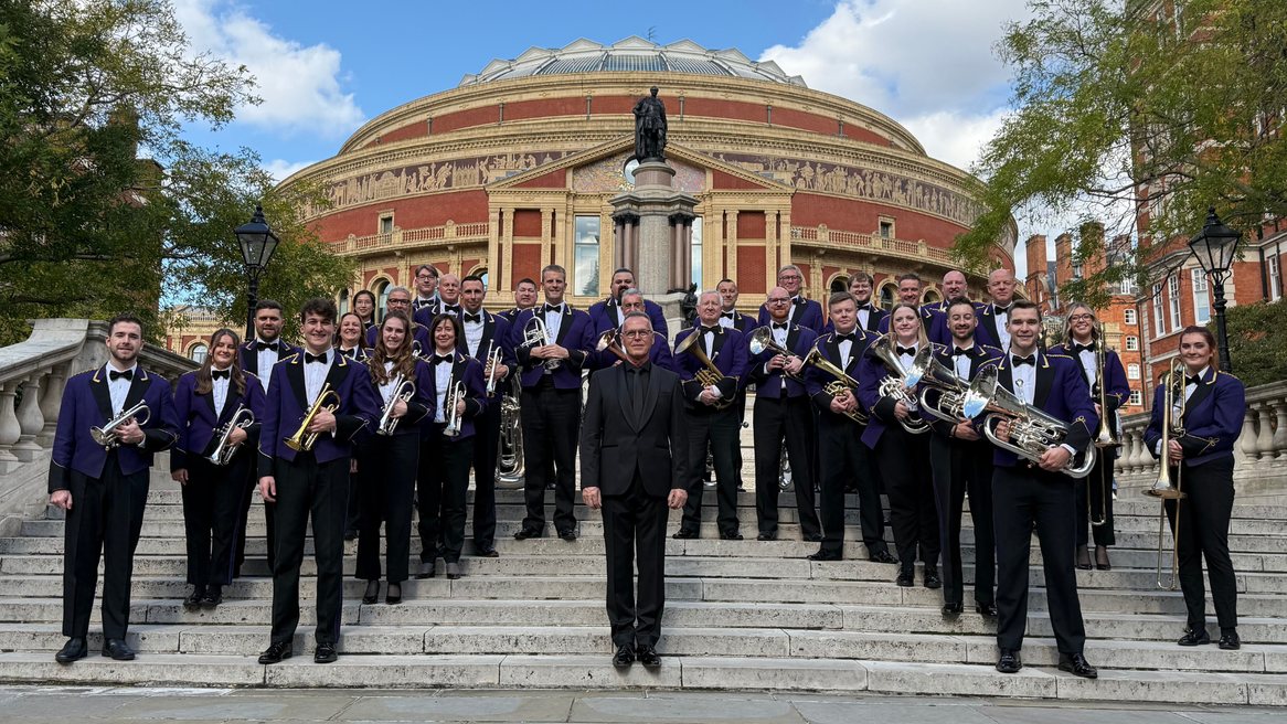 A brass band in purple band outfits stand in front of the Royal Albert Hall