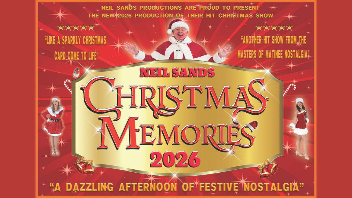 A man in a Santa Claus outfit smiles with his arms outstretched as two young women in Santa themed dresses pose