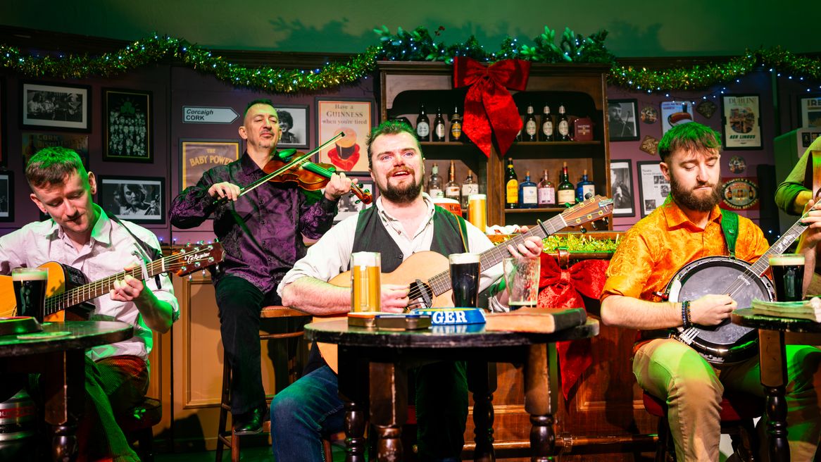 Irish musicians play instruments in a pub decorated for Christmas