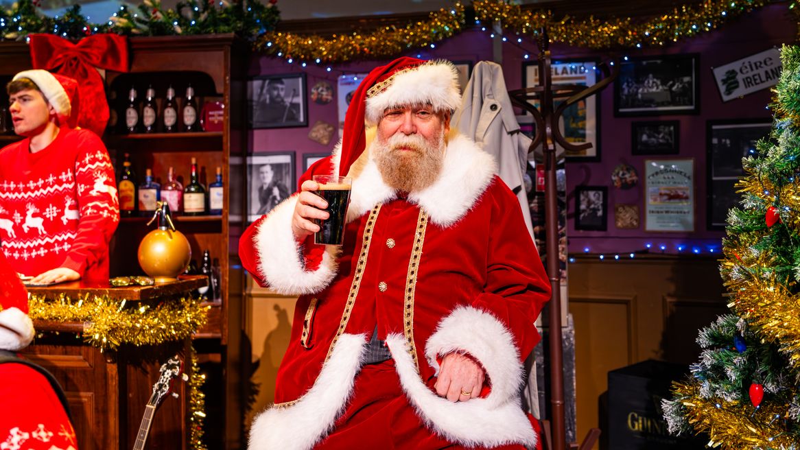 A man dressed like Father Christmas holds a pint of Guinness