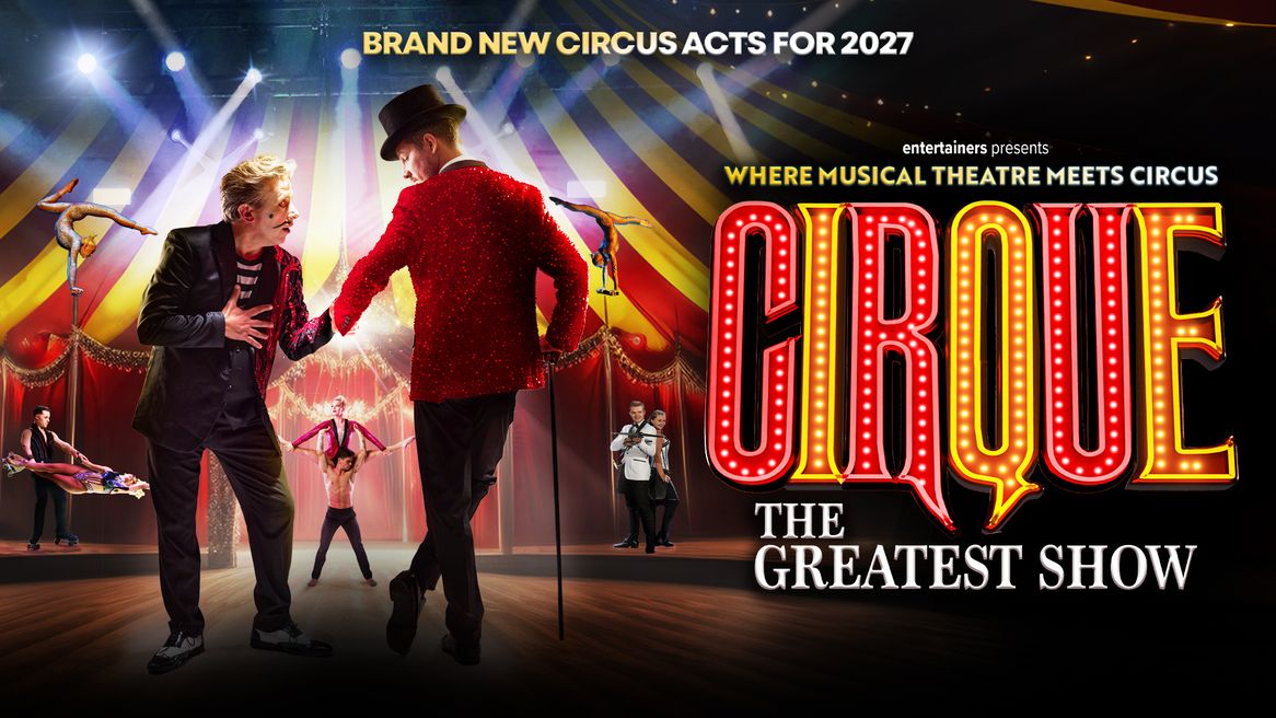 A man in a sparkly red jacket and a top hat stands next to aclwon in front of a big top full of circus performers