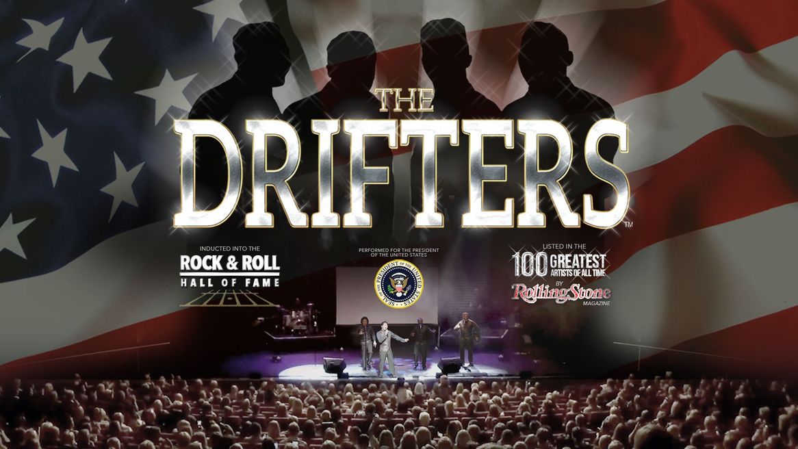 Four men perform on stage in front of a large crowd in front of the words The Drifters