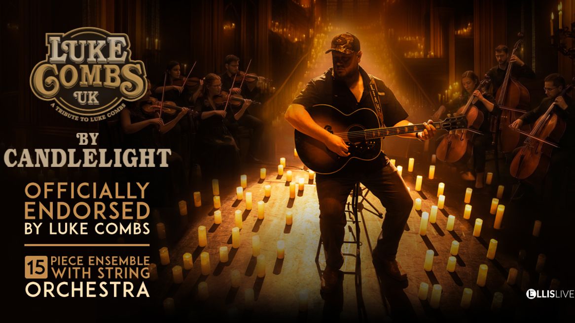 A man wearing a baseball cap plays guitar surrounded by candles and a string orchestra