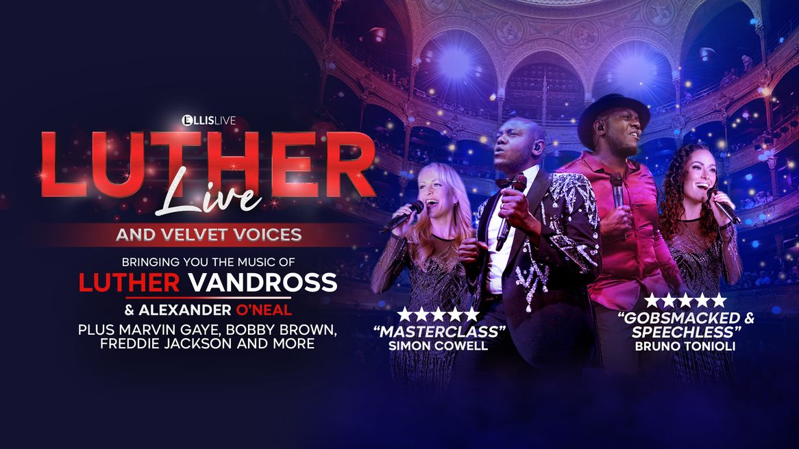 Two men dance with microphones alongside two female backing singers in front of a packed auditorium