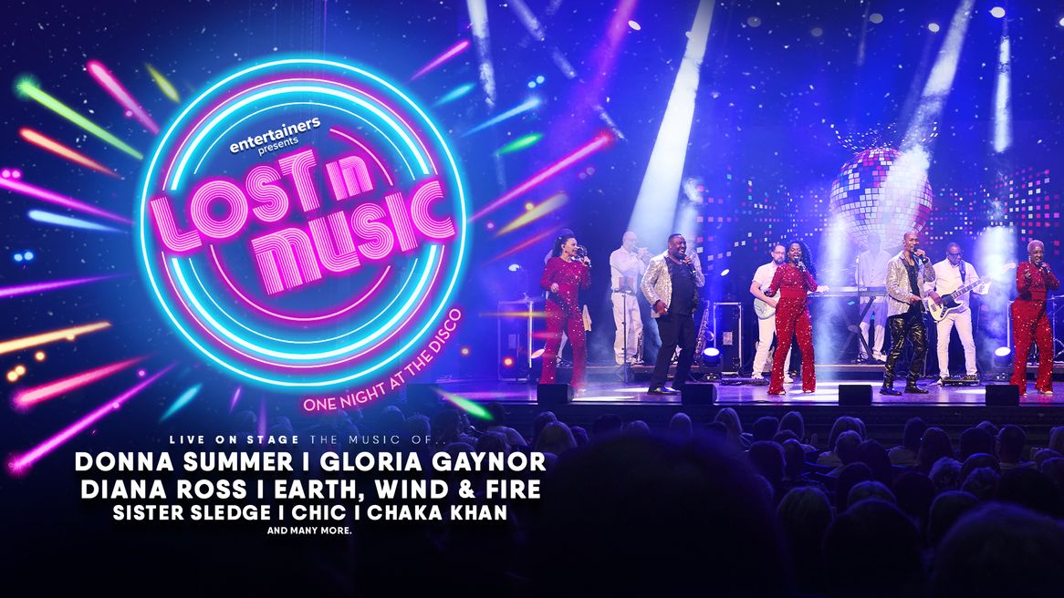 Three women and two men perform with a live band in front of a disco ball