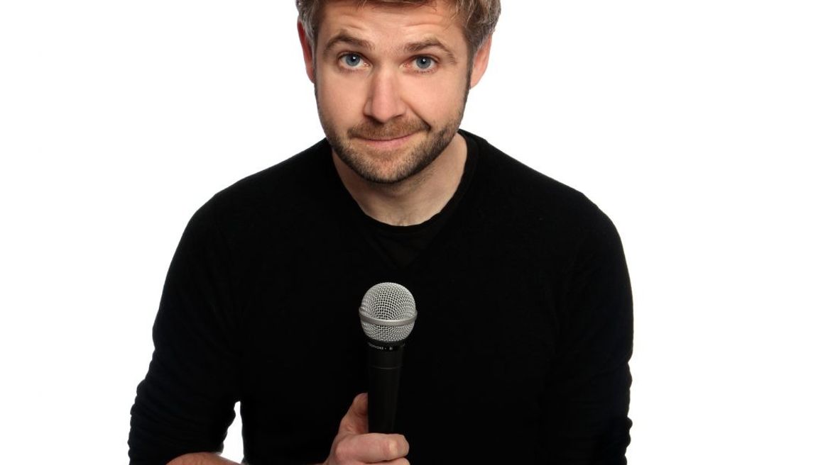 Comedian with a microphone looking straight at the camera