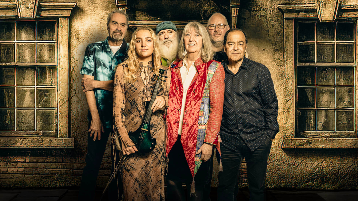 Two women and four men stand tother in front of an old building