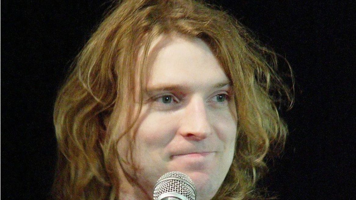 Comedian Sean Percival smiling in fromt of a microphone