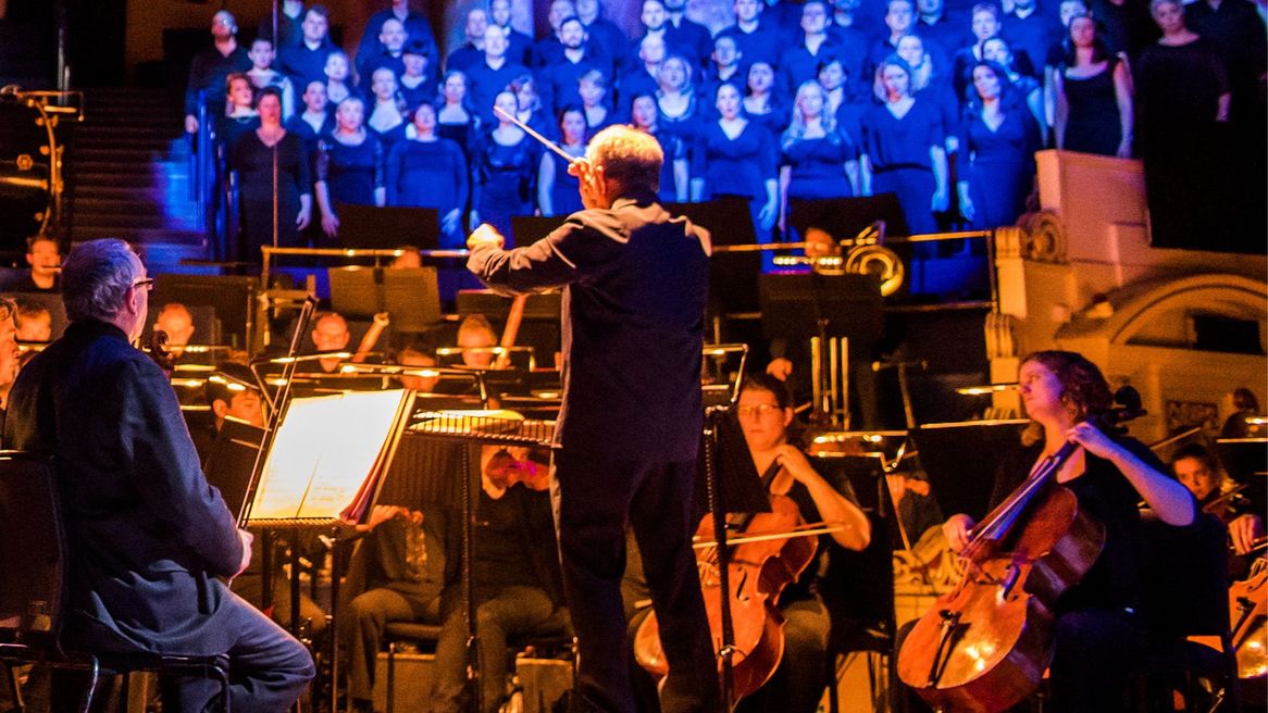 Man conducting a male and female choir singing 