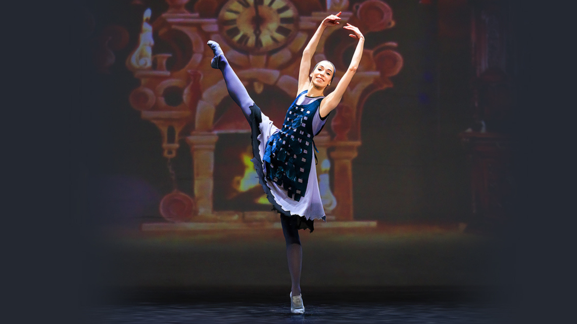 A ballet dancer in a dress made of rags dances in front of a large clock