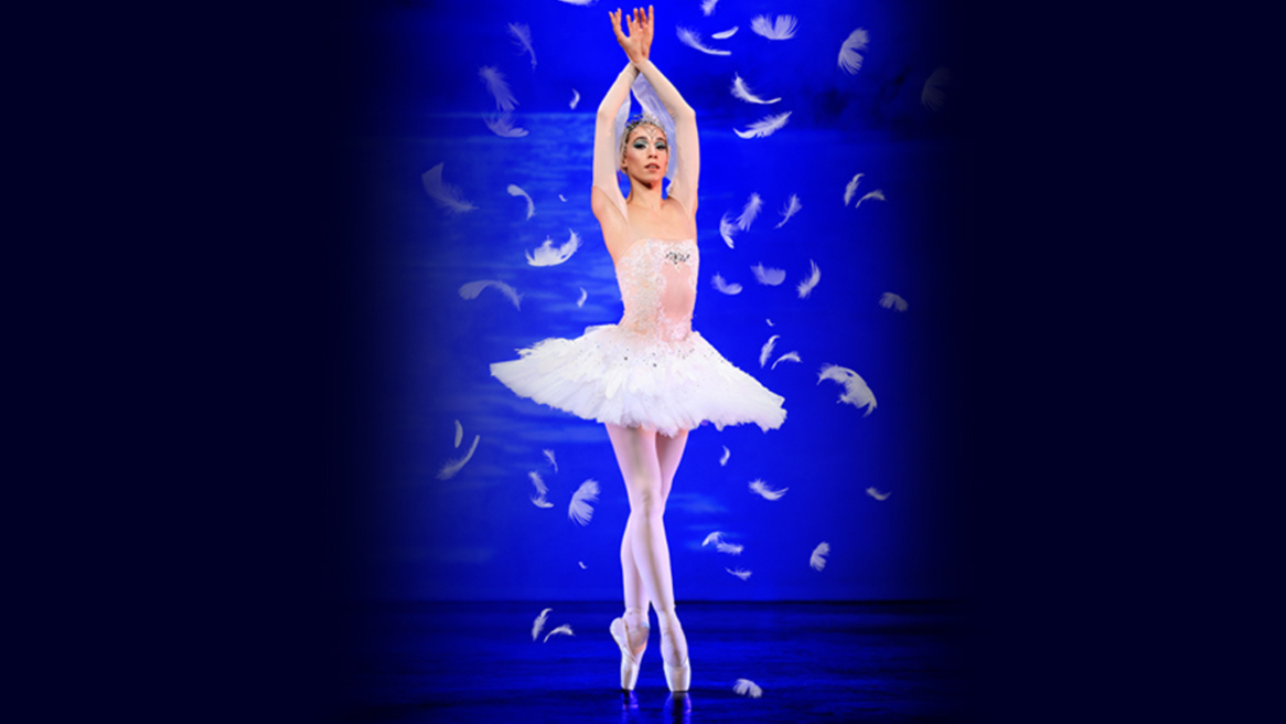 A ballerina in a white feathered tutu poses while feathers fall to the ground