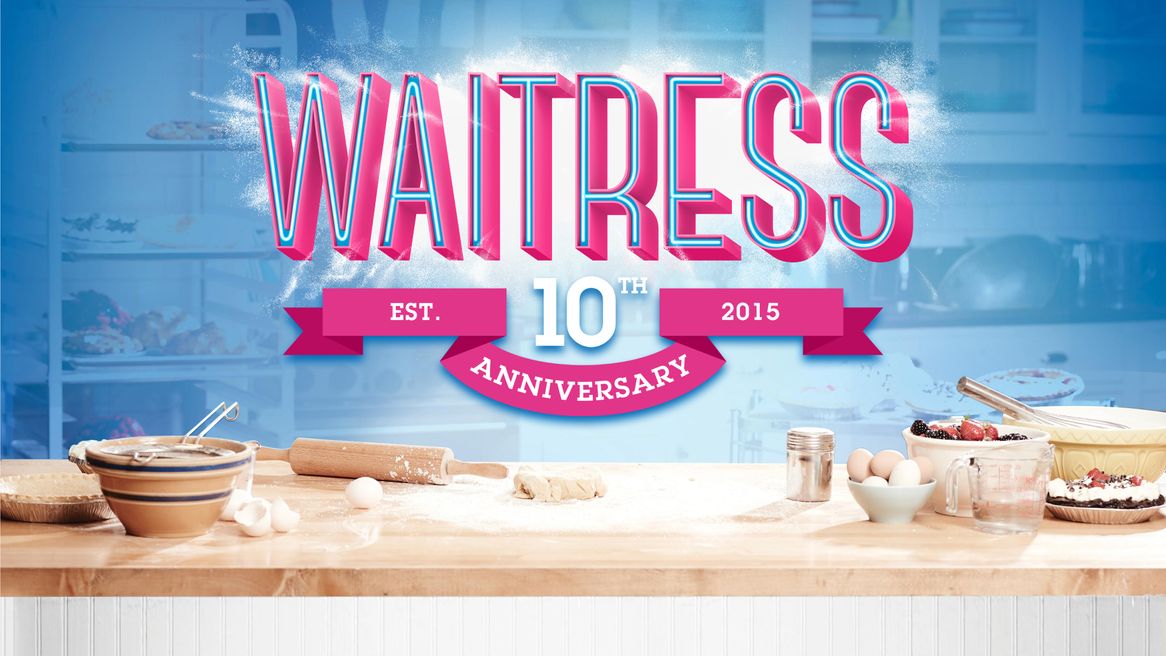 The Logo Waitress above a kitchen table with ingrediants including eggs and flour ready to bake a cake. 
